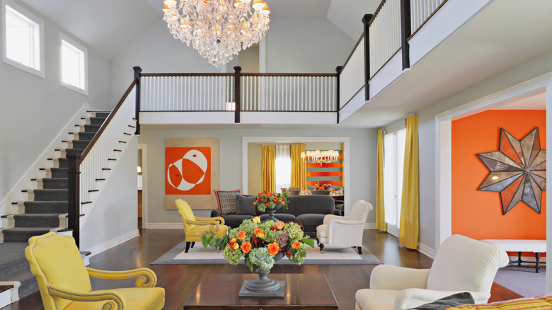 Living room with yellow vibrant yellow chairs and orange accent wall and vibrant orange painting