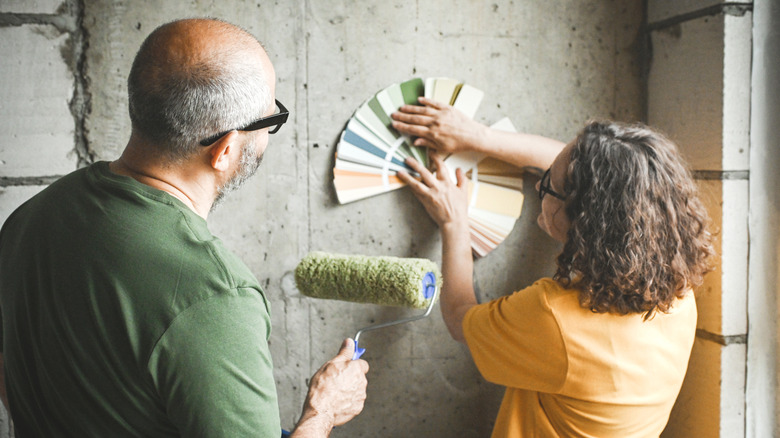 A couple looking at paint samples against a wall